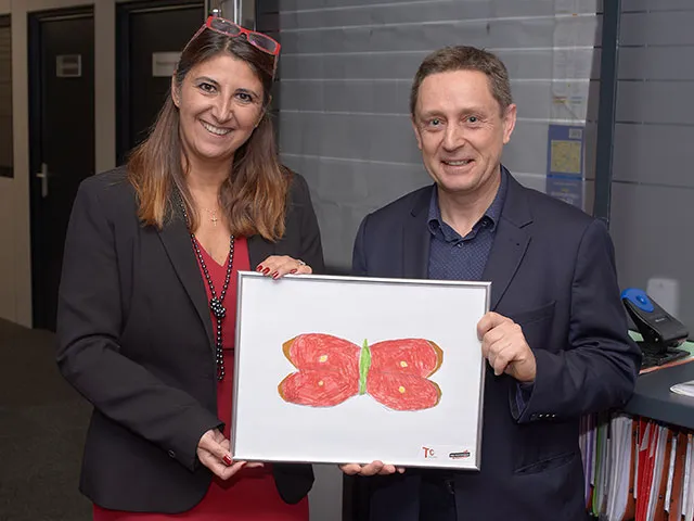 Photo de Philippe Mandier et de madame Chaix tenant un dessin de papillon intégré au logo de TC Transport