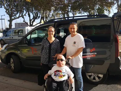 Photo de 3 personnes dont une en fauteuil devant un véhicule aménagé TC Transport